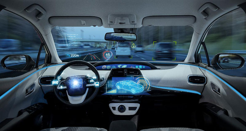 Interior of a vehicle with lighted dashboard and cars around it on a highway